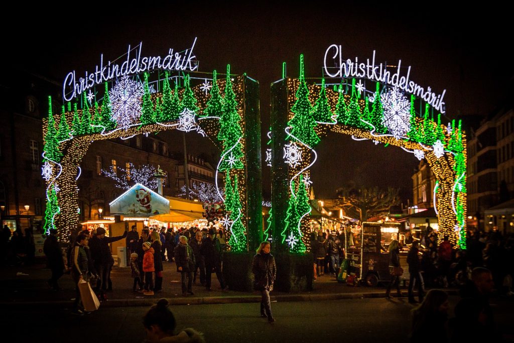 Entrada al mercado navideño de Estrasburgo con luces verdes y gente