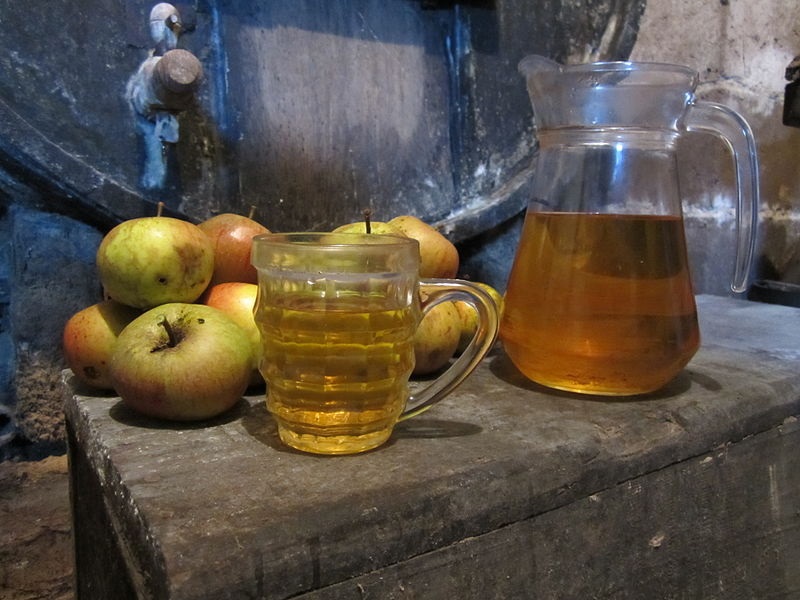 Manzanas, jarra de sidra, vidrio y barriles de la bodega de Normandía