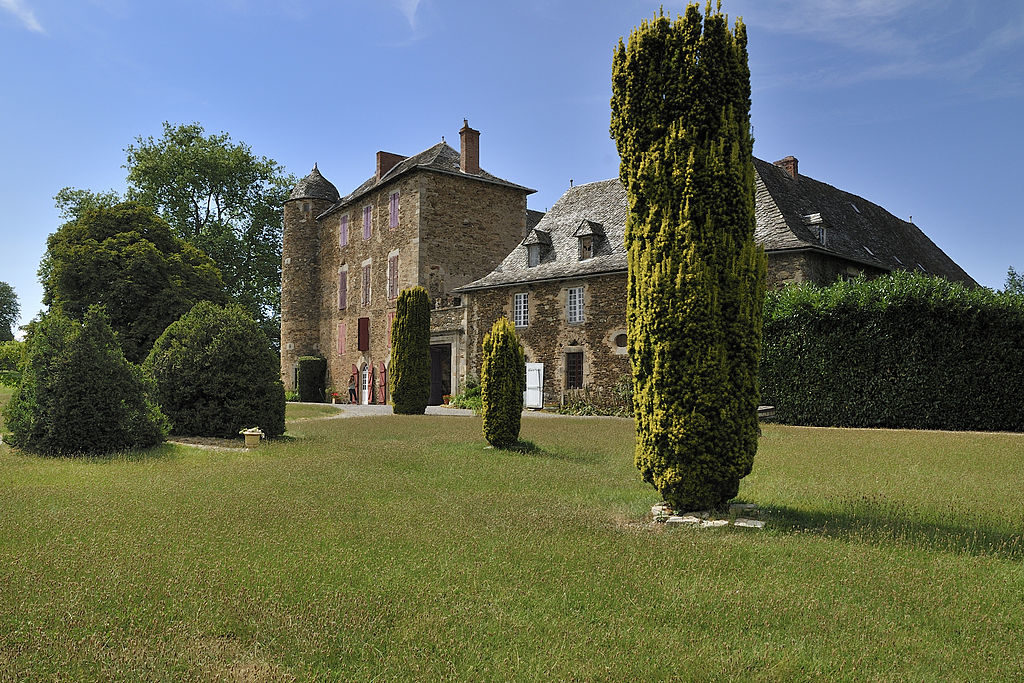 Una vista de un campo y árboles frente al Chateau du Bosc en la región de Aveyron