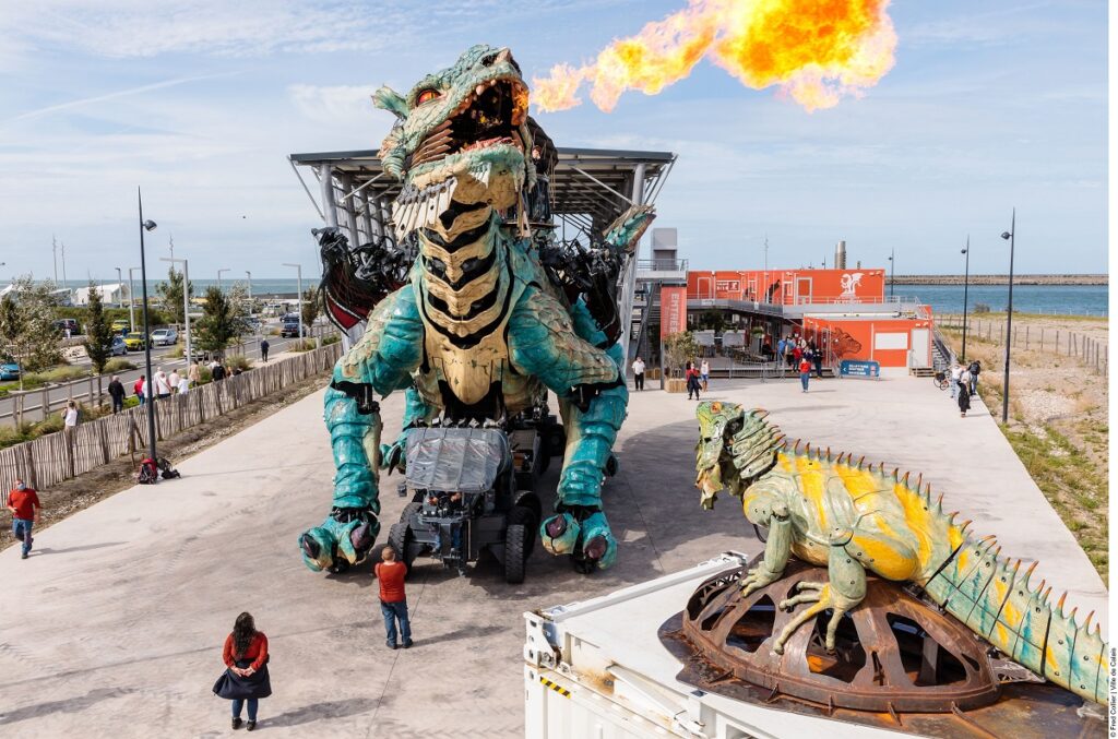 Modelo de iguana en la parte delantera derecha del contenedor mirando hacia Calais Dragon mientras está lleno y respirando fuego