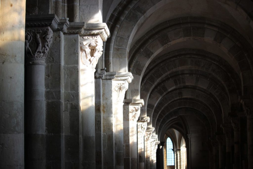 Dentro de la basílica de Vézelay con luz brillando en las caras de piedra tallada de los capitolios