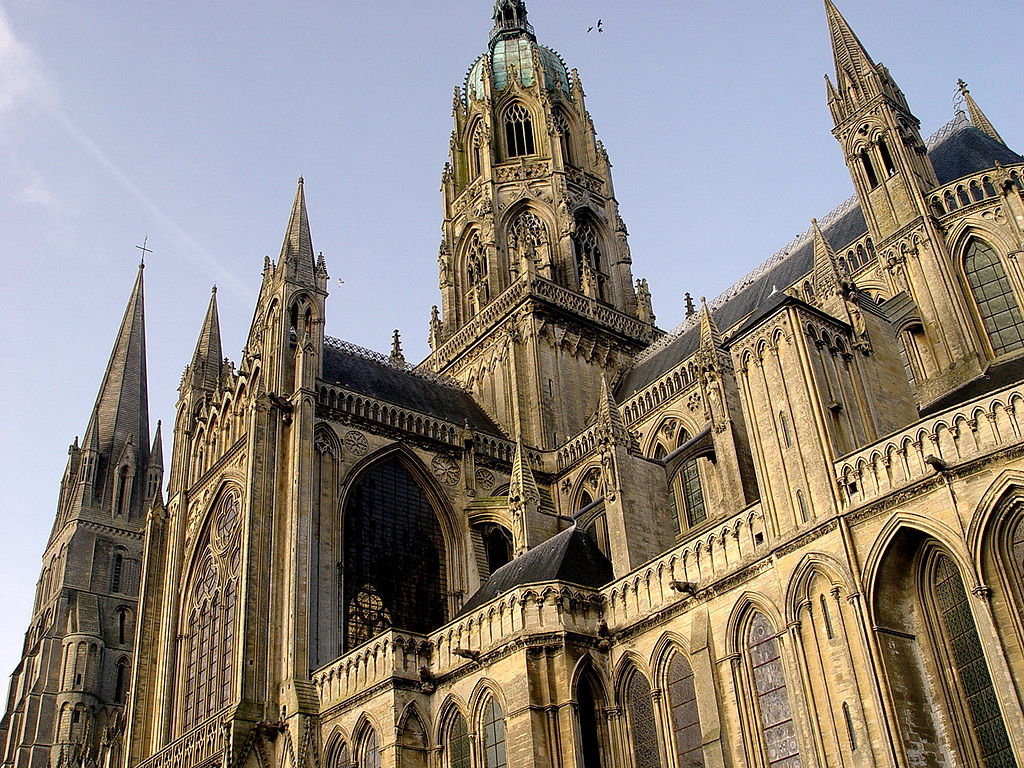 Mirando hacia la vista lateral de la Catedral de Bayeux con torres altas en los arcos medio e inferior, así como contrafuertes voladores