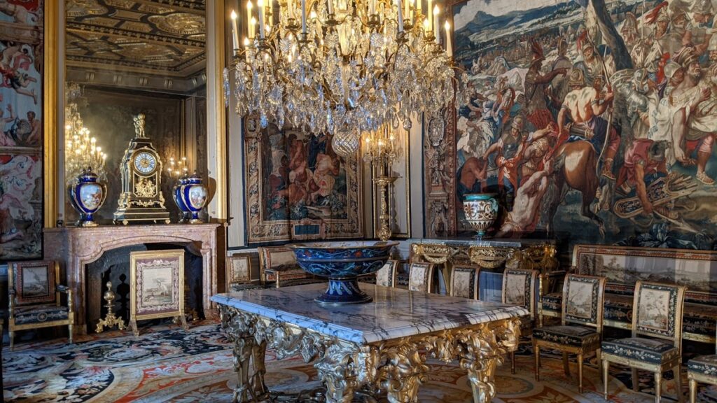 Sala de recepción de Ana de Austria en Fontainebleau que muestra una habitación muy ricamente decorada con tapices en la pared, una enorme lámpara de araña dorada, muebles de mármol