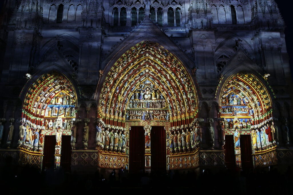 Una pantalla de luces de colores brillantes sobre la puerta principal de la catedral de Amiens por la noche