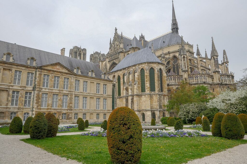 La catedral de Reims se erige en el fondo detrás del ornamentado Palais de Tau neoclásico y un jardín verde en el frente