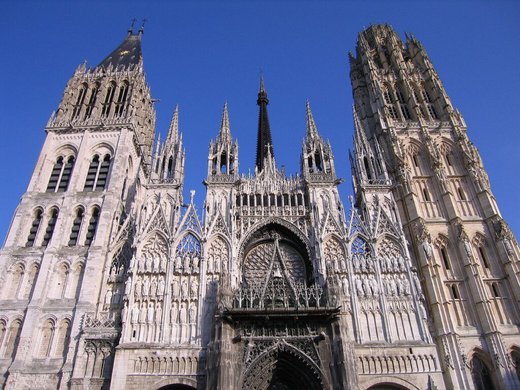 Mirando hacia el frente de la Catedral de Rouen que muestra torres e intrincados trabajos en piedra