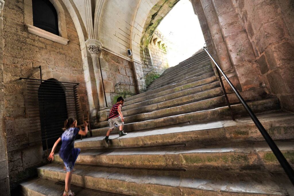 amplia escalera de piedra que conduce al interior de Rocamadour con dos niños subiendo escalones