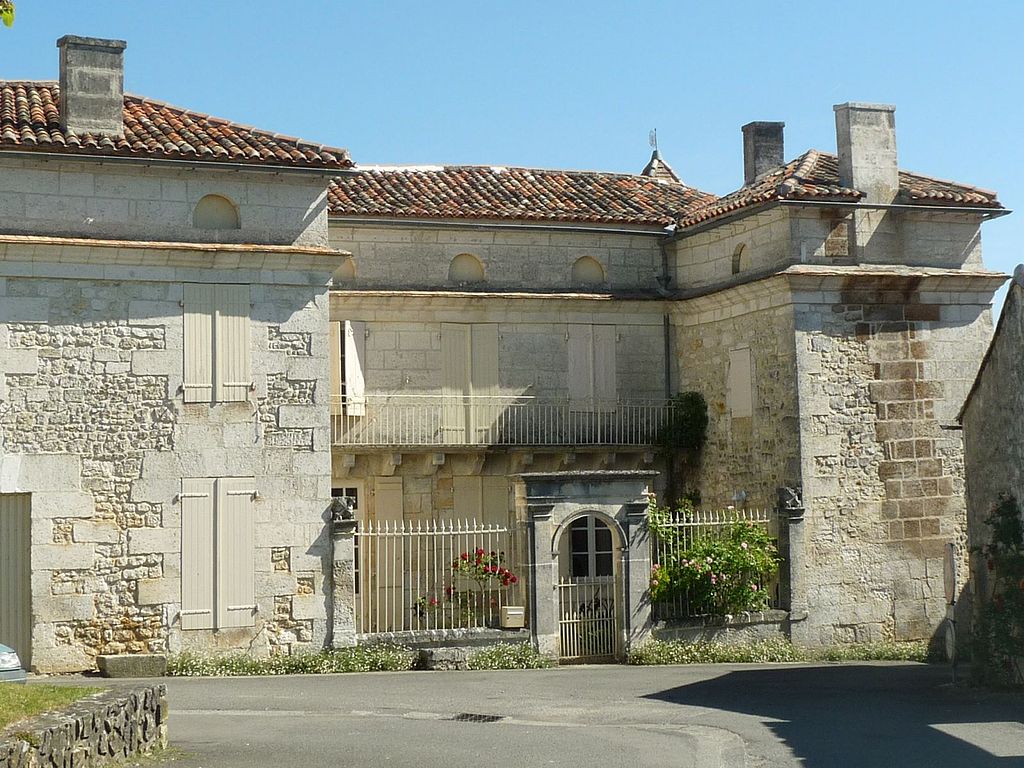 Casa Charentaise de pisos de piedra que muestra una puerta que conduce a un pequeño patio con una casa en tres lados