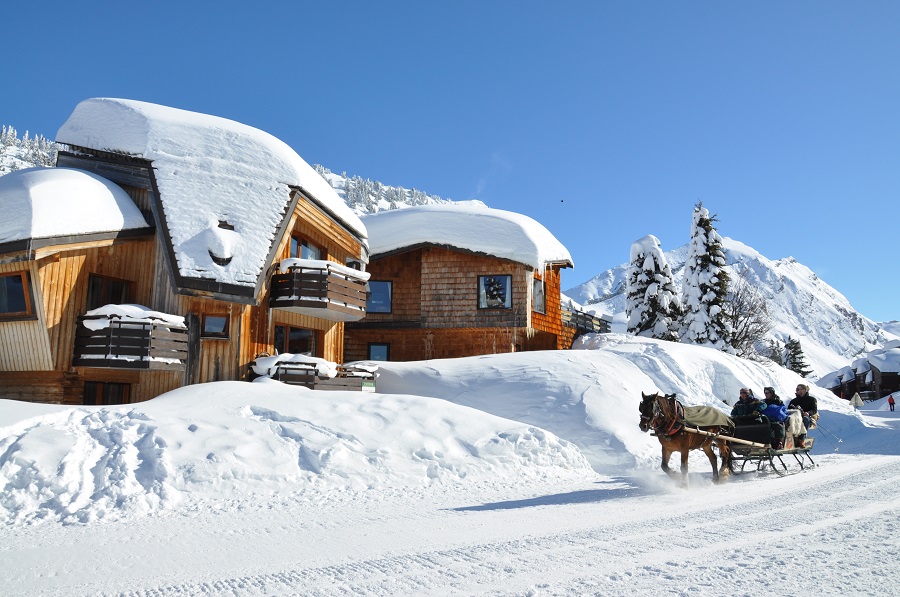 modernas salas de esquí en Avoriaz con ángulos extraños y voladizos utilizando madera y estilo tradicional básico. De pie junto a la carretera cubierta de nieve con un caballo y una trampa que se avecina