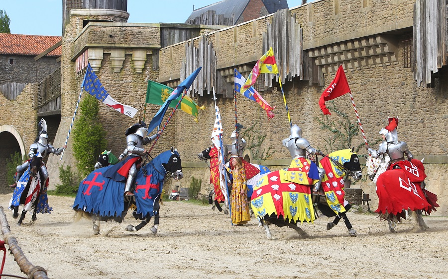 Caballeros de Puy du Fou a caballo con armas y mangueras cubiertas con largas banderas que fluyen cargando hacia adelante