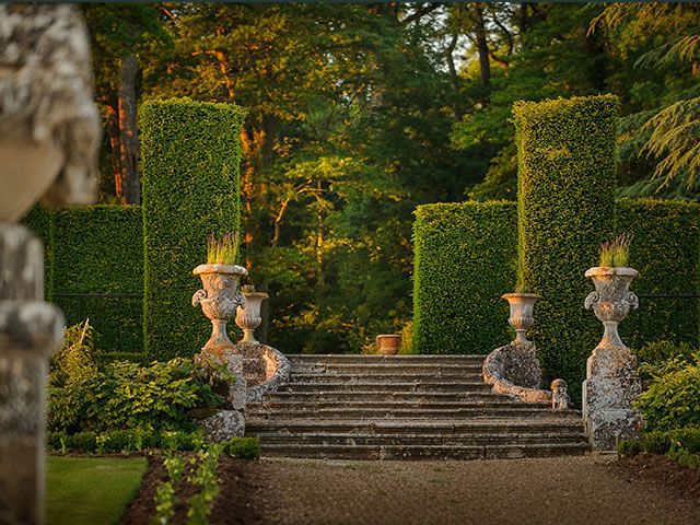 Jardines del Chateau de Valmer mostrando clásicas capillas de piedra con plantas escalonadas con tejos formados en círculos y un fondo verde