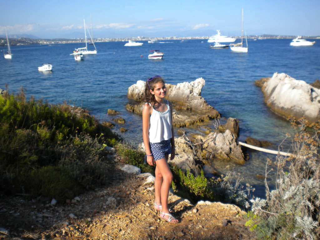 Una niña en el promontorio de Ste Marguerite con mar y yates en el fondo