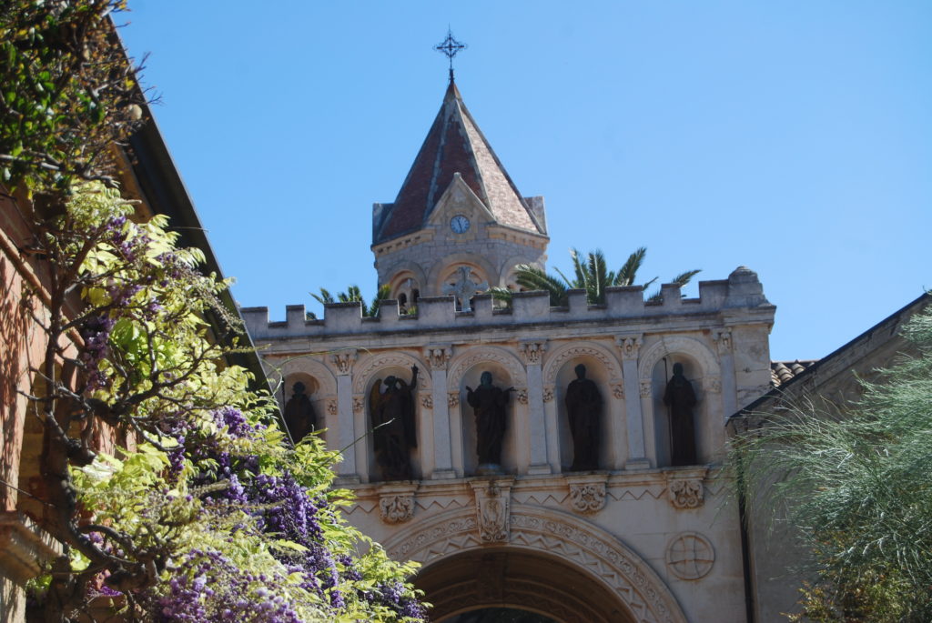 Torre del monasterio contra el cielo azul y los árboles en primer plano Ile St Honorat