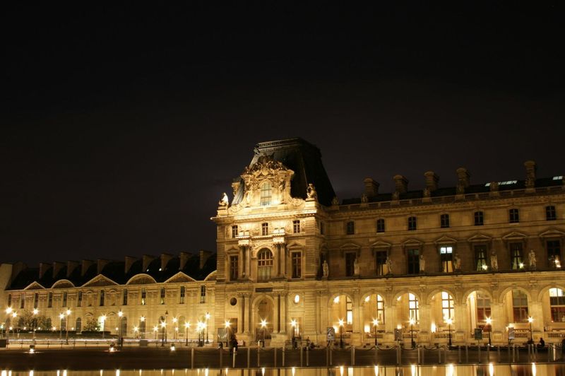 La fachada del Louvre de París iluminada de noche