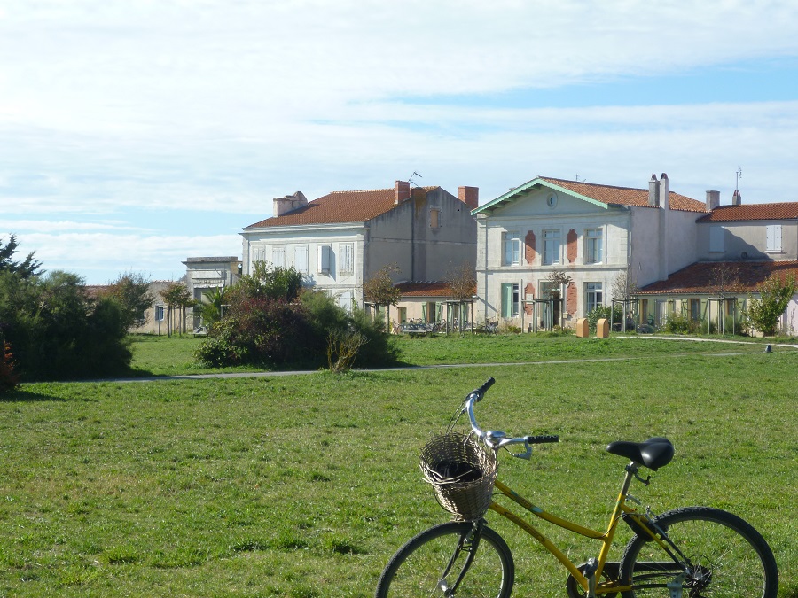 bicicleta en primer plano en la Place d'Austerlitz en Ile d'Aix con césped verde respaldando casas de 2 plantas en bonitos colores