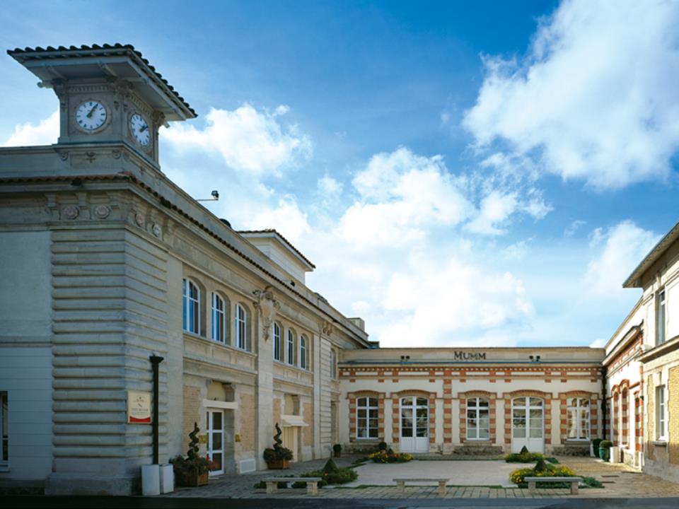 Exterior de Champagne Mumm en Reims con un patio y edificios de piedra de 2 pisos que lo rodean