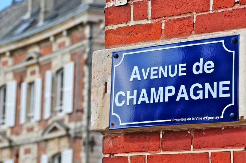 Avenue de Champagne Blue firmar en Epernay contra una pared de ladrillo rojo.