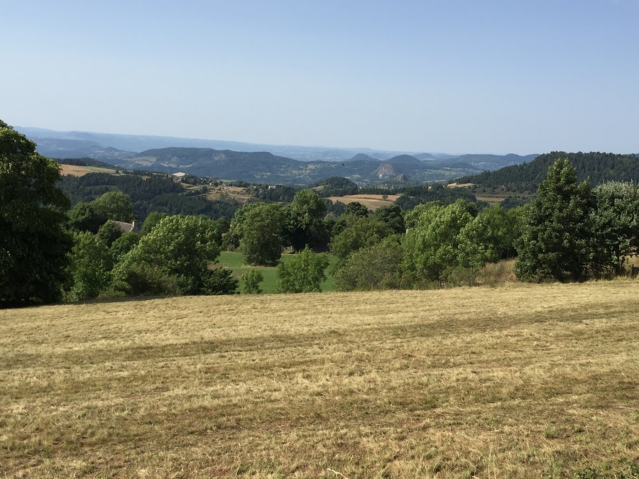 Vista de Auvernia desde la cima de una colina alta con vistas al campo amarillo cosechado a colinas y valles en segundo plano.