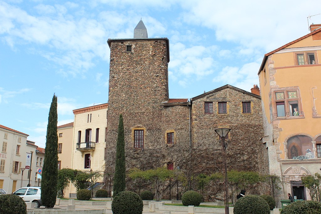 Antiguo castillo en Roanne en calle con gran torre cuadrada y edificios más pequeños y casa en frente