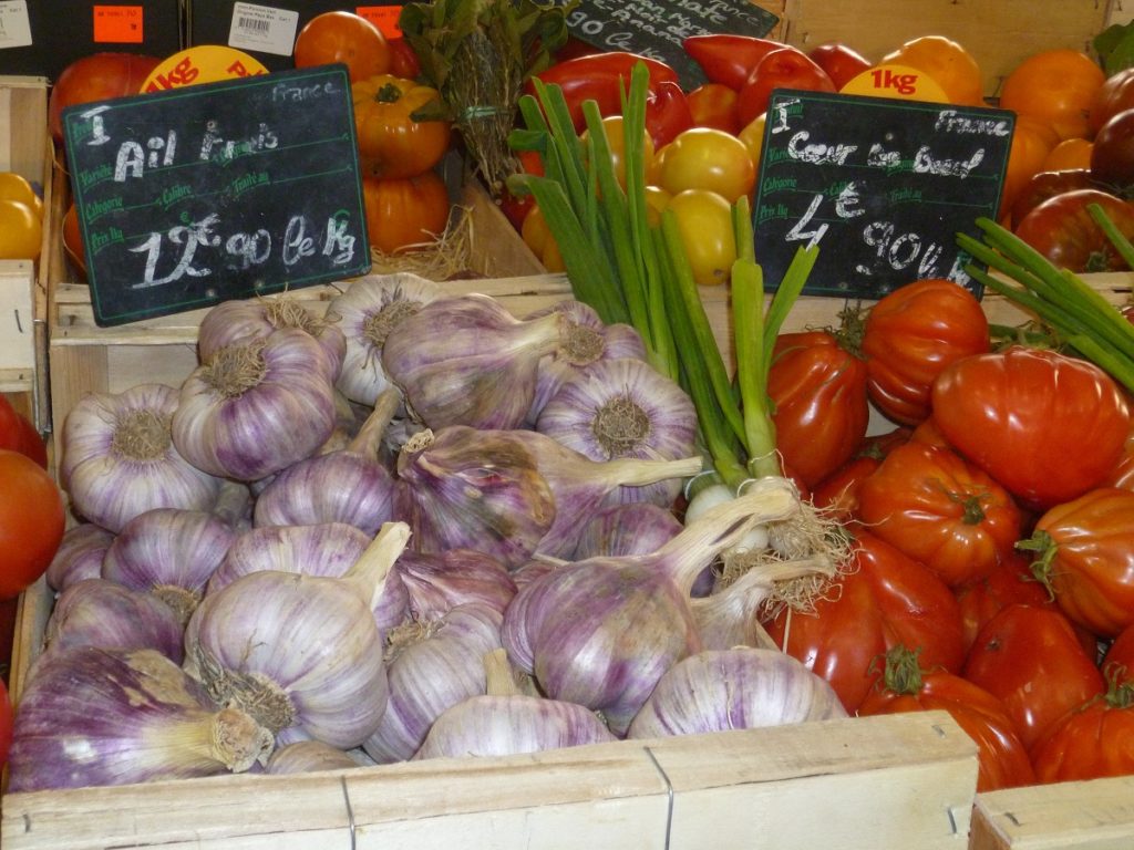 Puesto en el mercado de Antibes con ajo, tomates y cartel de precio