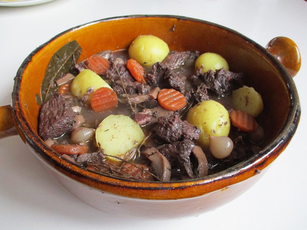 Un plato rústico de terracota marrón con dabe de ternera y verduras