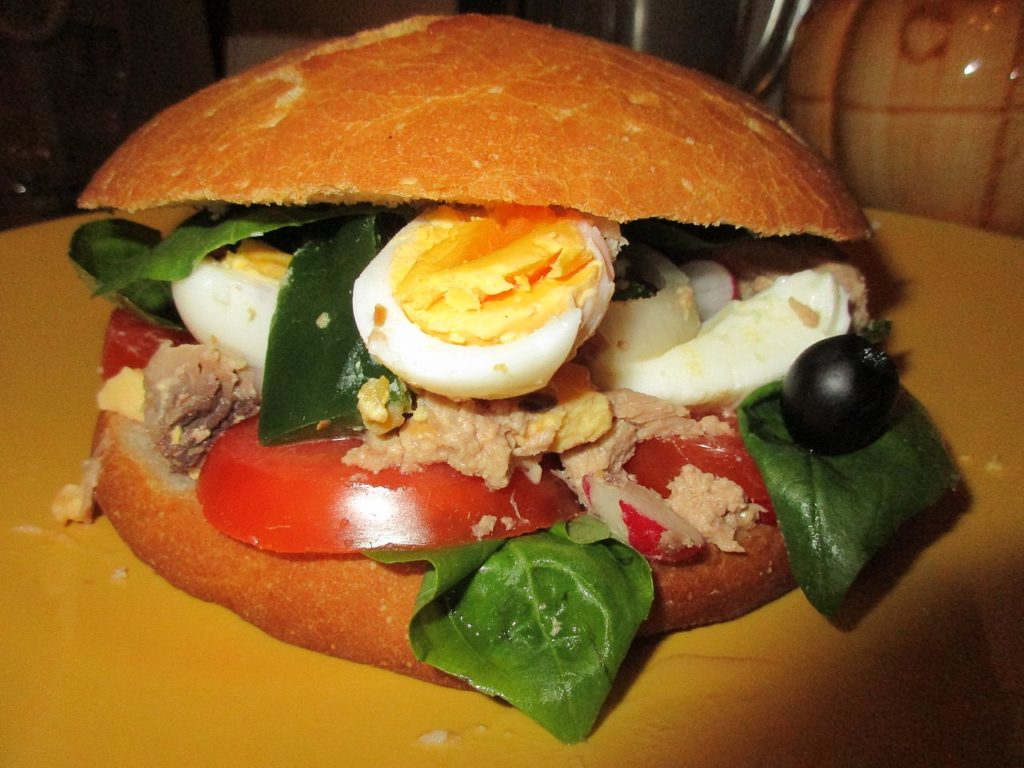 Bun Pan Bagnat con huevos duros, tomate, atún y hojas de albahaca