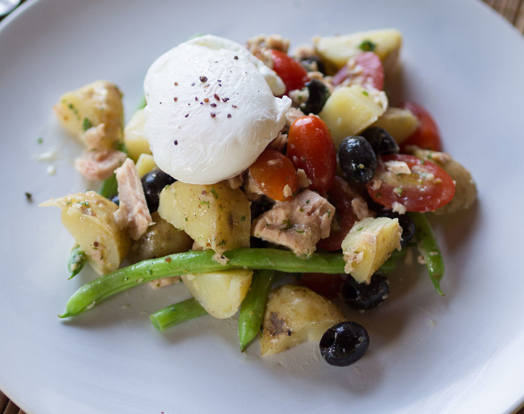 Ensalada niçoise con lechuga, patatas, queso, tomate, pescado y alubias