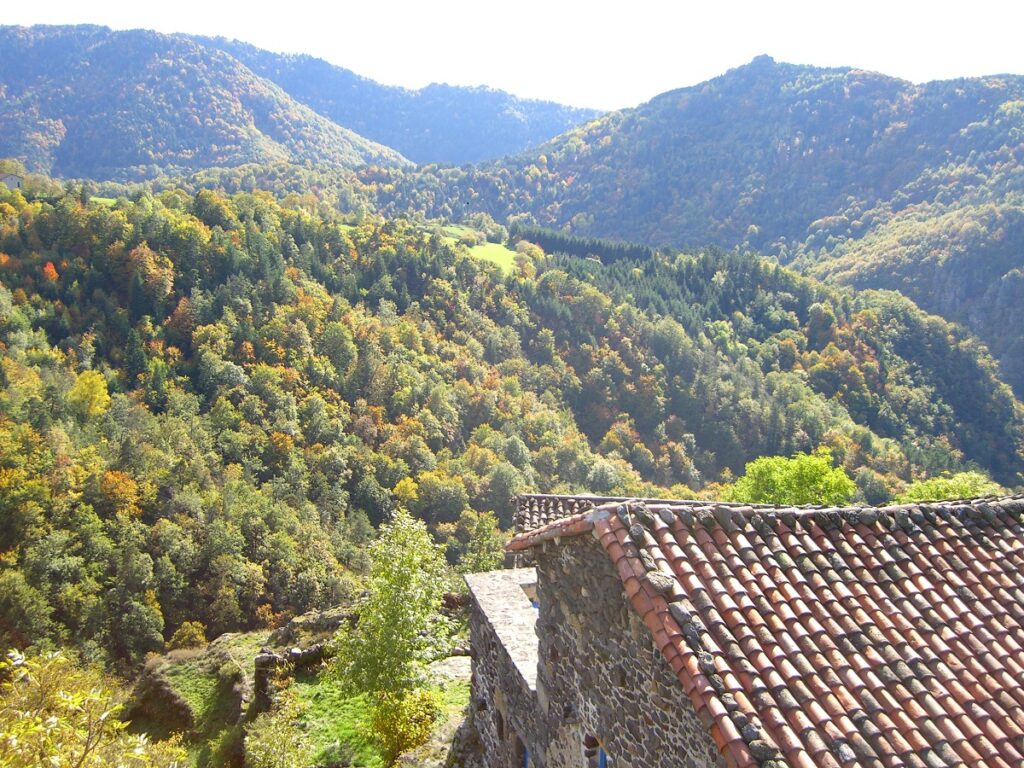 Una vista sobre el valle del río y las altas colinas en la distancia con la casa roja debajo 