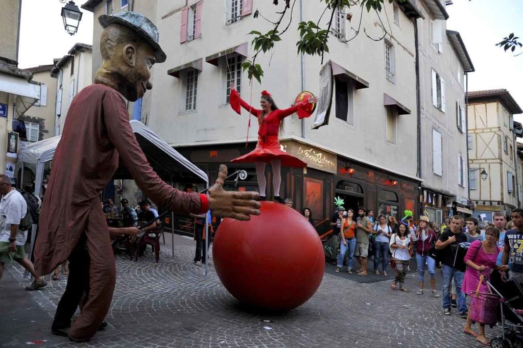 Un hombre vestido con una gran bola roja en las calles de Aurillac en el festival de teatro