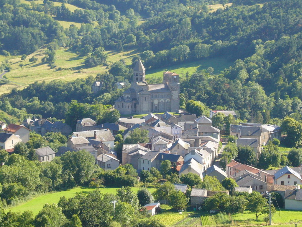 Vista aérea de Naomh Necaire con su catedral a lo lejos y casas alrededor. Todo en el campo.