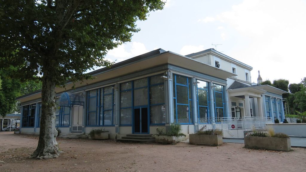 Un café Art Deco en Vichy con una fachada azul y blanca, paredes de vidrio y acero