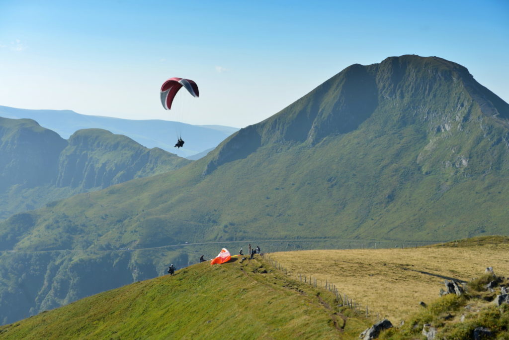 Vista de parapentes en Auvernia contra un fondo de montaña volcánica