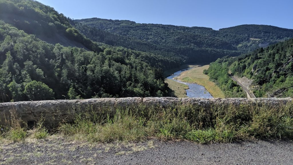 Mirando hacia abajo desde el camino de la pared de piedra en las gargantas de Allier y la vía del tren junto al río