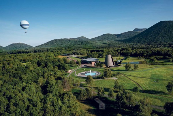 Vista aérea de Vulcania en Auvergne, un parque temático volcánico con un edificio cónico y las montañas circundantes