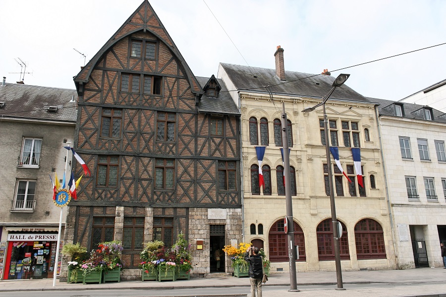 Maison Jeanne d'Arc en Orleans con un antiguo edificio de 4 plantas de ladrillo rojo y entramado de madera flanqueado por otros edificios antiguos