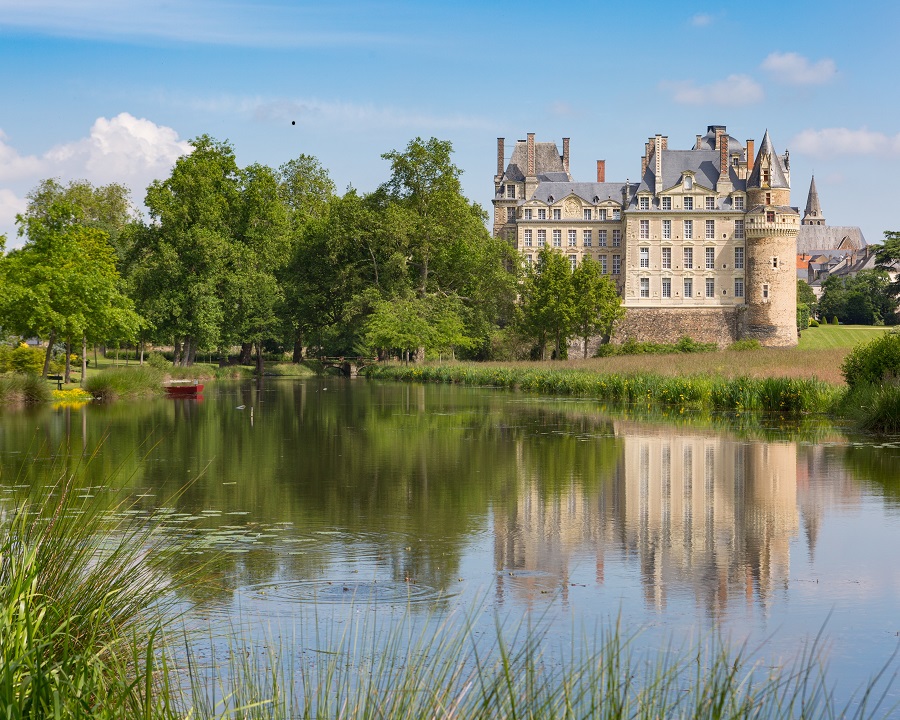 Loire Valley Château deBrissac con un gran lago en frente y árboles a la izquierda y en la distancia un Chateau de 7 pisos reflejado en las aguas