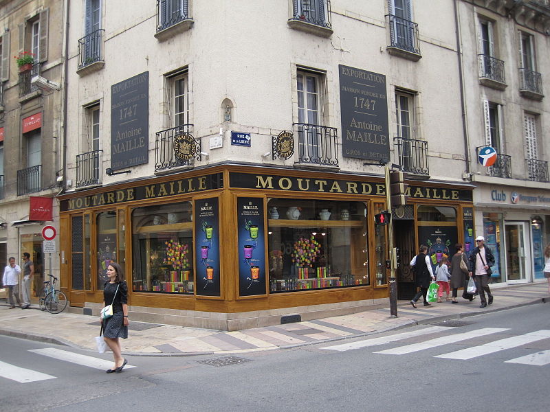 Tienda de la esquina de Malle Dijon con nombre en el exterior y mostaza en la ventana