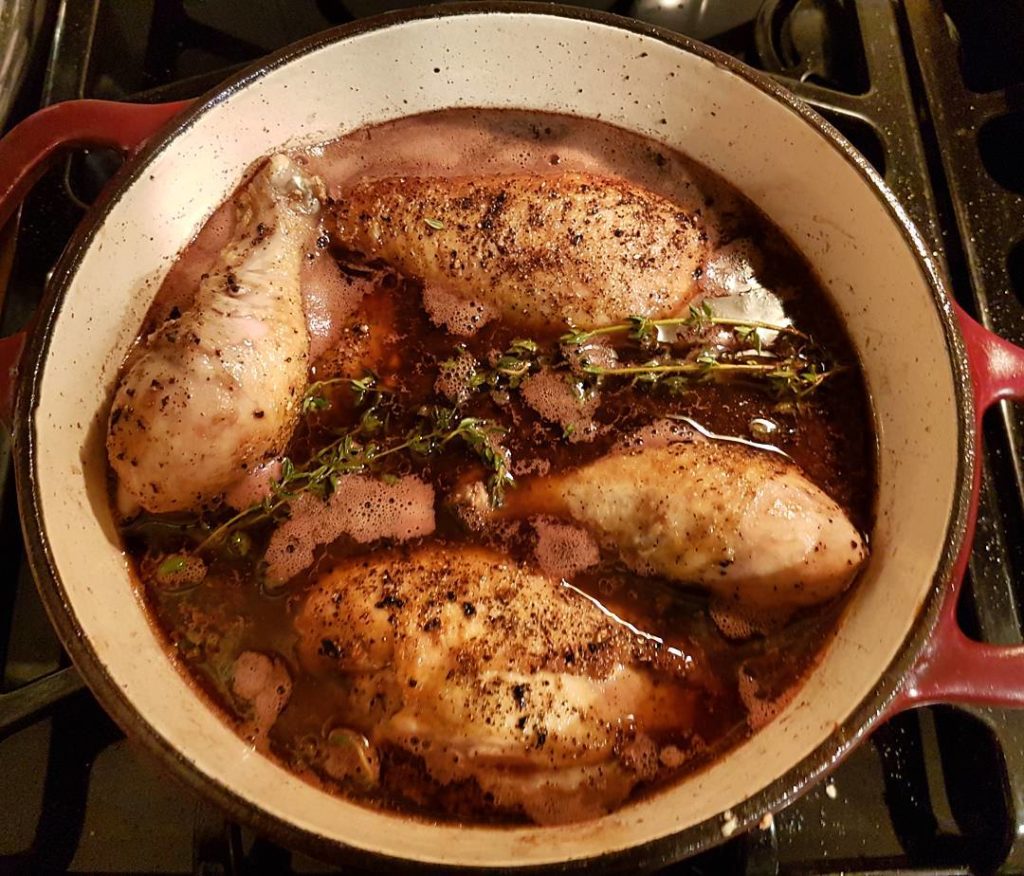 trozos de pollo en coq au vin en una olla redonda