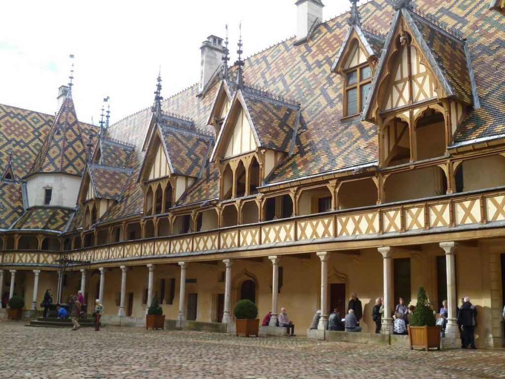 Hospicio de Beaune edificio en patio interior con galería de madera, impresionante techo de tejas y buhardillas puntiagudas