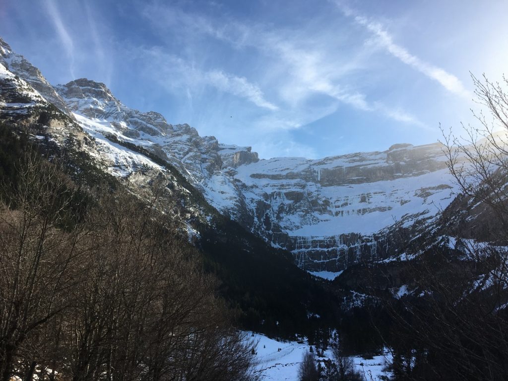 Cirque de Gavarnie con estelas de vapor en el cielo azul y picos nevados