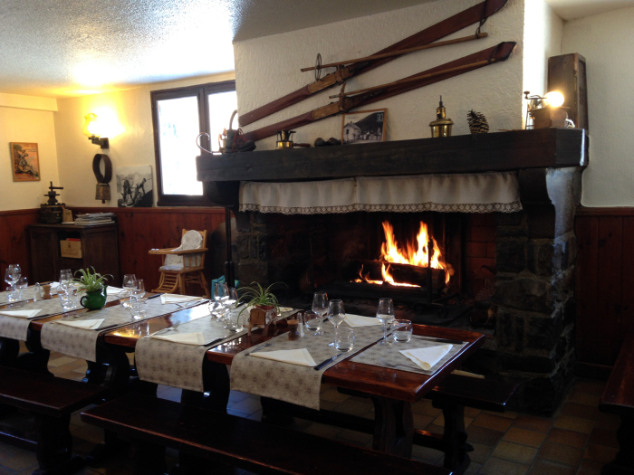 Chez Louisette adentro con una gran chimenea y mesas puestas frente a ella