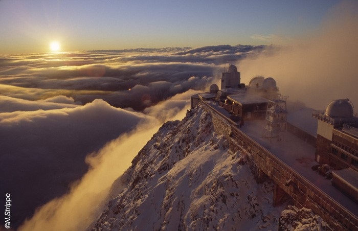 Vista de la estación Pic du Midi en la parte superior de Pic du Midi con montañas que se extienden detrás y niebla