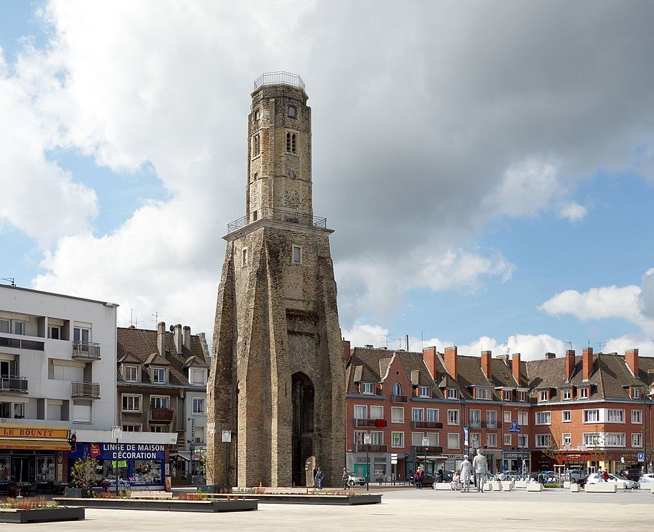 Tour du Guet en Calais. Una torre de piedra en el centro de la plaza con tiendas detrás y figuras en una plaza. Originalmente medieval