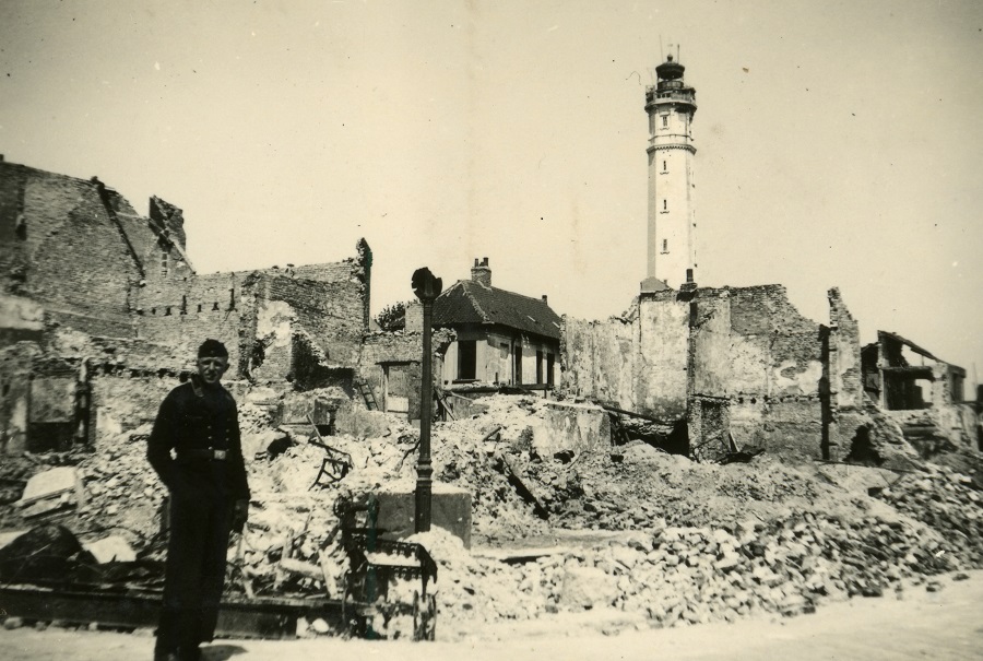 Antigua fotografía en blanco y negro de Calais en la Segunda Guerra Mundial. Un hombre de pie mirando el faro, el único edificio en pie entre los escombros de una ciudad bombardeada