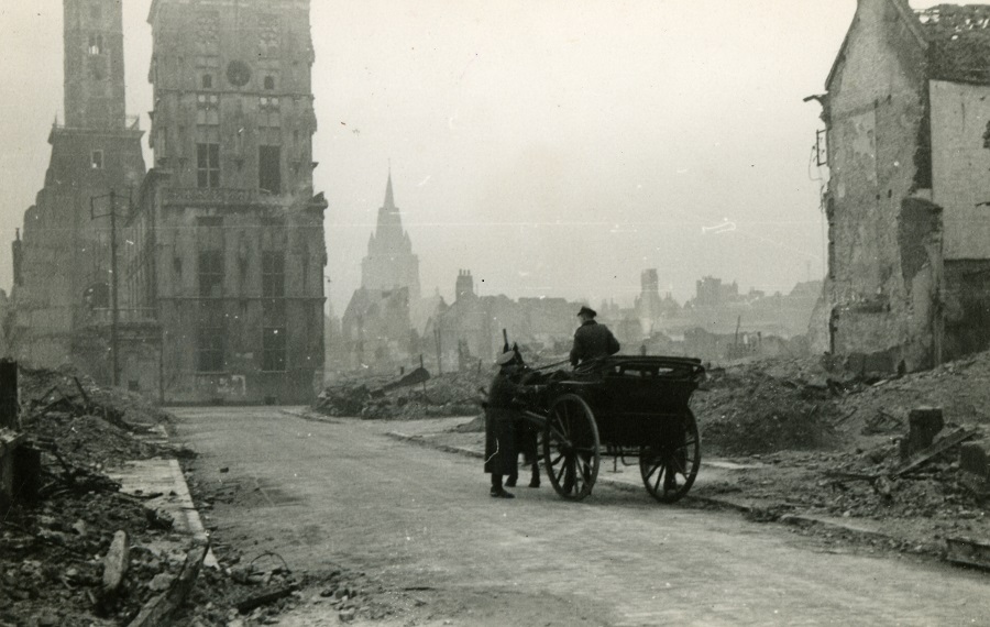 Una vieja fotografía en blanco y negro de Calais en la Segunda Guerra Mundial, con un caballo y un carro entre las ruinas, aunque el ayuntamiento aún se encuentra en la distancia.