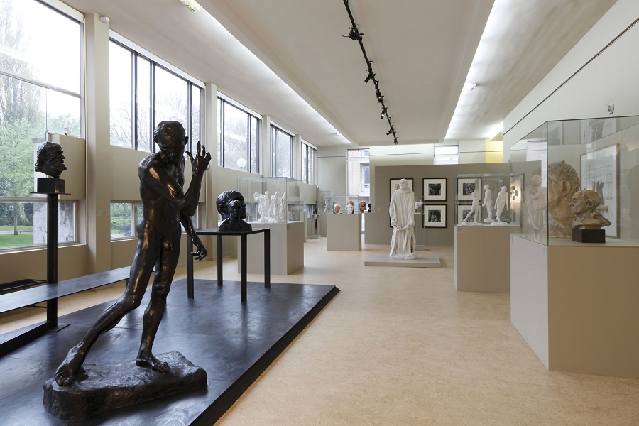 Museo de Bellas Artes de Calais mirando hacia una larga galería iluminada por ventanas a la izquierda. Con esculturas de tamaño natural de él mismo y pinturas en las paredes.