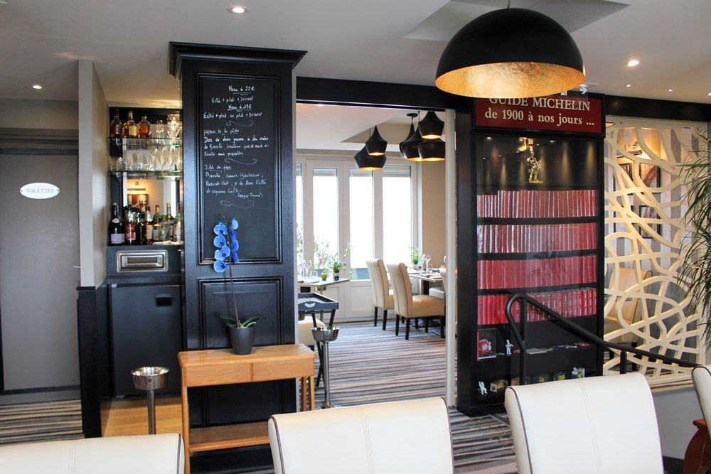 Interior del restaurante Le Grand Bleu que muestra la estantería a la derecha de la entrada abierta al comedor con mesas y sillas en el interior