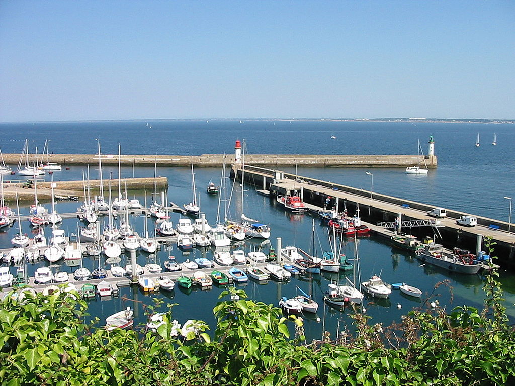 Vista desde lo alto de Port Tudy, Ile de Groix, islas de Bretaña con muchos yates amarrados en un puerto deportivo protegido del mar por grandes diques