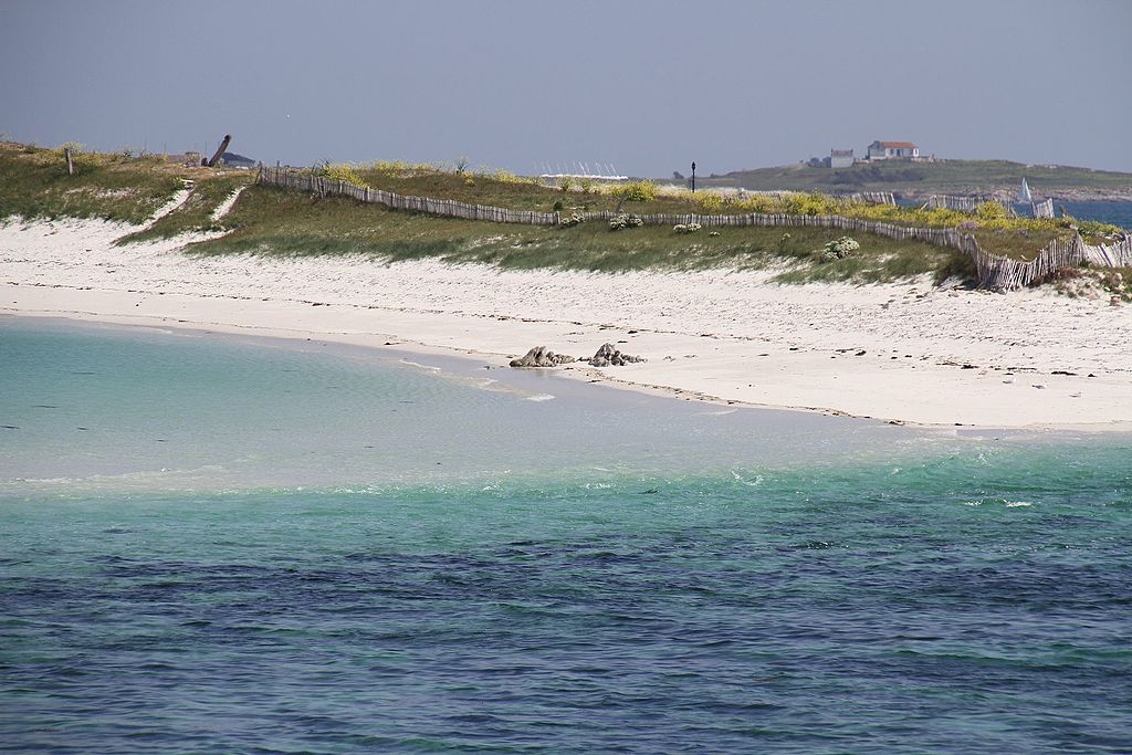 La vista de las islas desde Glennan desde Bretaña desde el mar azul y luego turquesa y luego acercándose a una playa de arena blanca con pequeñas dunas detrás de ellas cubiertas de hierba