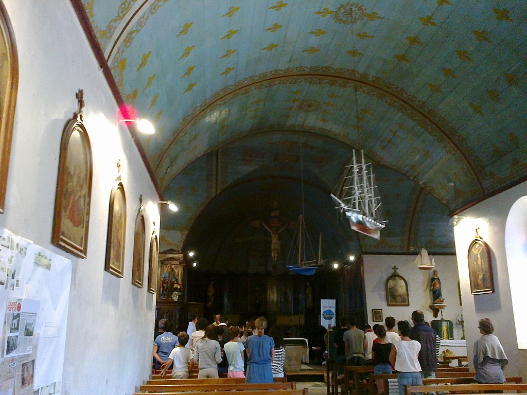 Hoedic de las islas de Bretaña dentro de la iglesia de un marinero con barcos colgando y al costado de la iglesia